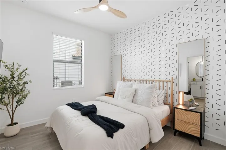 Bedroom with wood tiled floors, ceiling fan, and an accent wall