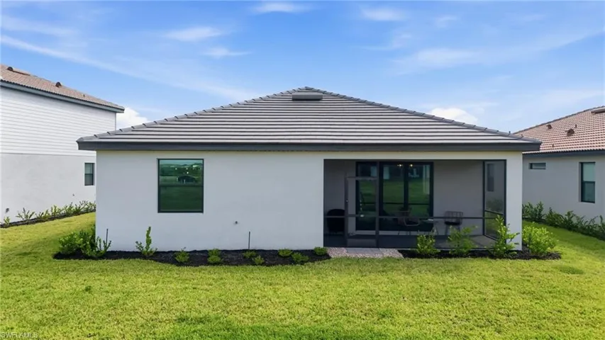 Back of house featuring stucco siding, a lawn, and a tile roof