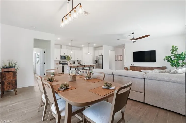 Dining space with wood tiled floors, ceiling fan, and recessed lighting