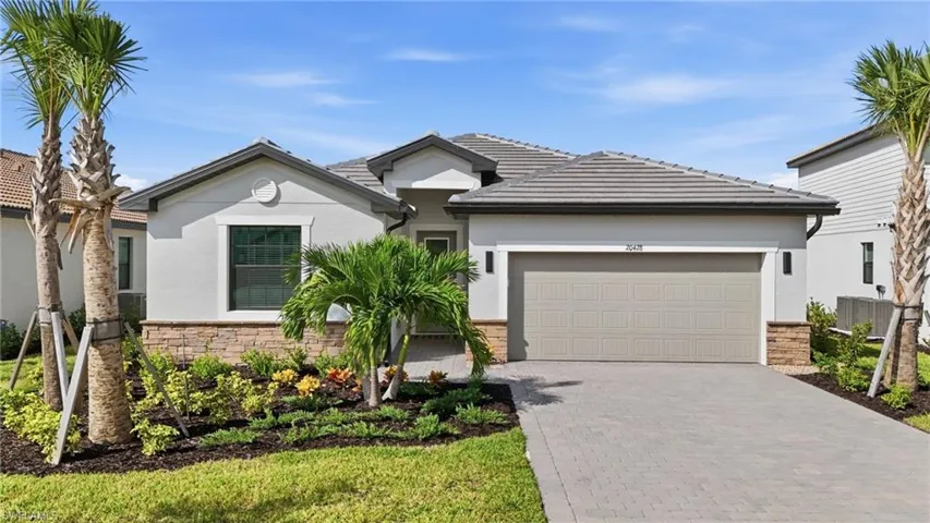 View of front of house featuring decorative driveway, stucco siding, stone siding, and an attached garage