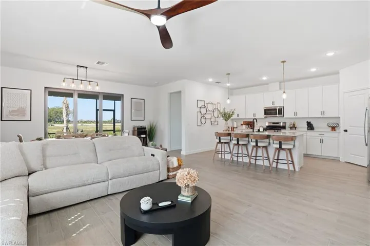 Living room with recessed lighting, a ceiling fan, and light wood-style flooring