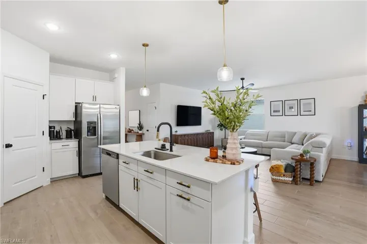 Kitchen featuring white cabinets, open floor plan, hanging light fixtures, and light wood-style flooring
