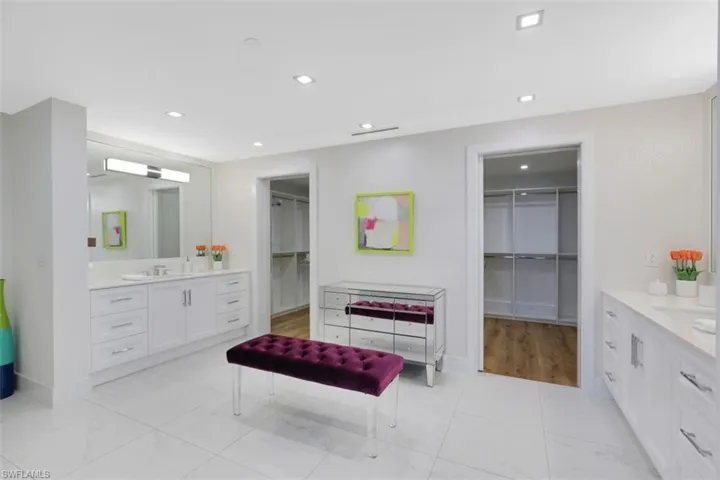 Full bath with two vanities, a walk in closet, and recessed lighting