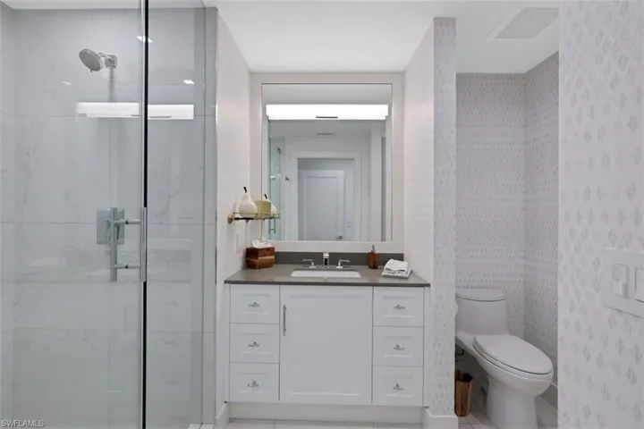 Full bathroom featuring a shower stall, vanity, and wallpapered walls