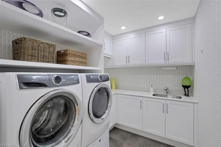 Laundry room featuring washing machine and dryer, cabinet space, and tile patterned floors
