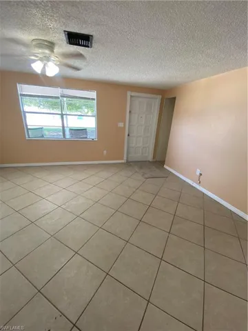 Spare room with tile flooring, ceiling fan, and a textured ceiling