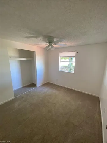 Unfurnished bedroom with a textured ceiling, ceiling fan, a closet, and carpet floors