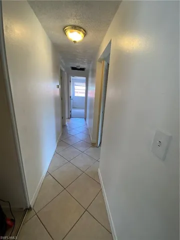 Hallway with a textured ceiling and light tile flooring