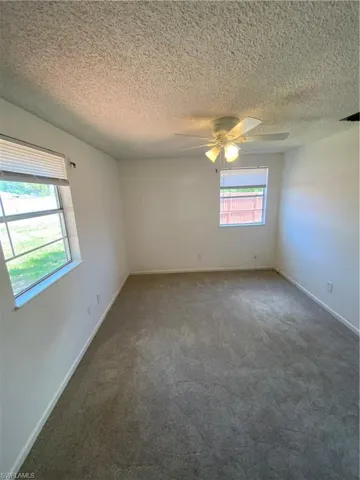Carpeted spare room with a textured ceiling and ceiling fan
