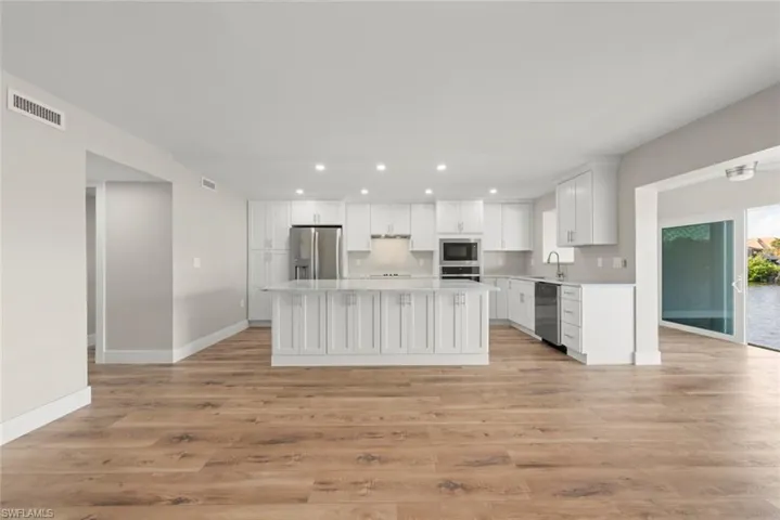 Kitchen with white cabinetry, recessed lighting, light wood-style flooring, a kitchen island, and appliances with stainless steel finishes