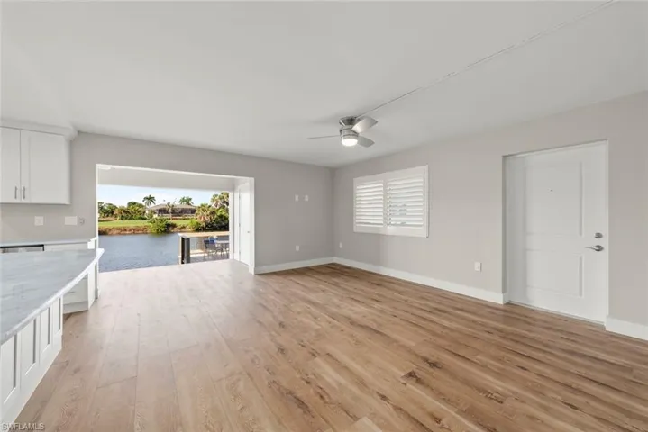 Unfurnished living room featuring light wood-style flooring, ceiling fan, and a water view