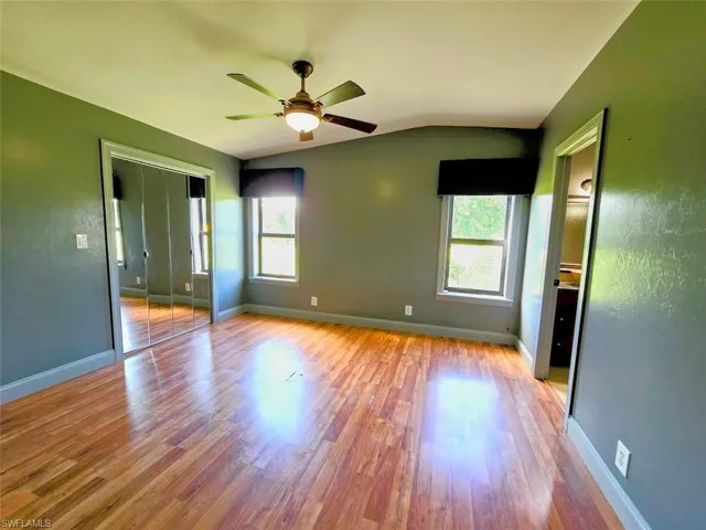 Spare room with ceiling fan, hardwood / wood-style flooring, and lofted ceiling