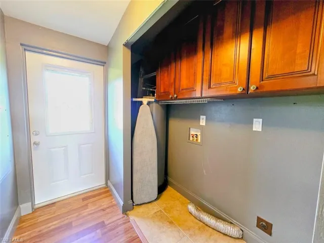 Laundry room with light hardwood / wood-style floors, hookup for a washing machine, hookup for an electric dryer, and cabinets