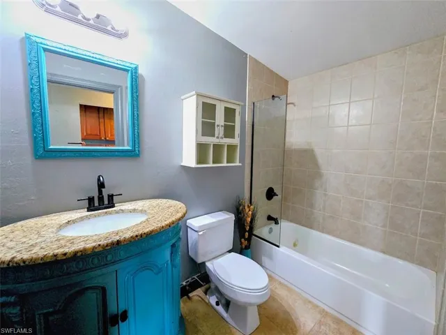 Full bathroom featuring tile patterned floors, tiled shower / bath, vanity, and toilet