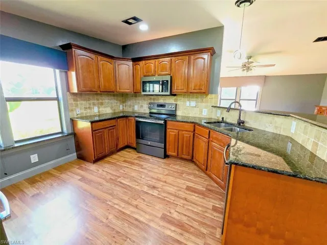 Kitchen featuring a wealth of natural light, light hardwood / wood-style flooring, backsplash, and stainless steel appliances