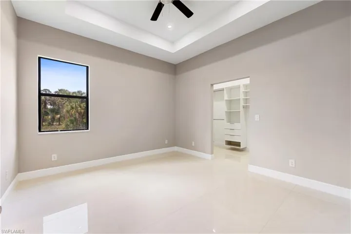 Empty room featuring a raised ceiling and ceiling fan
