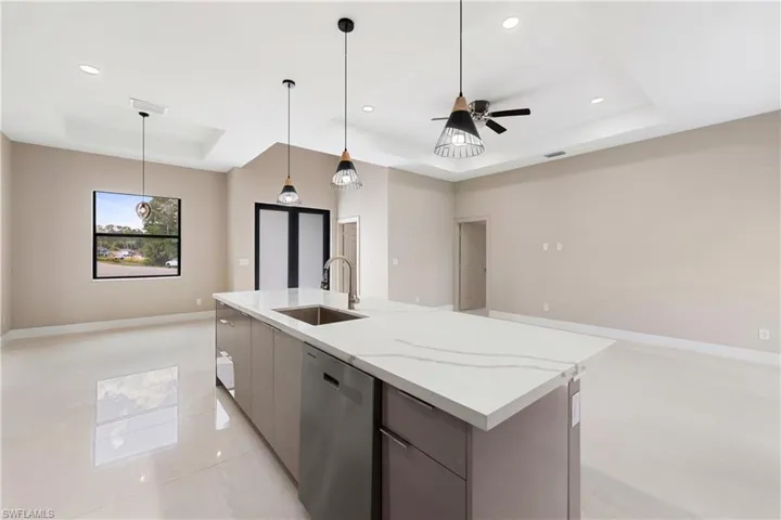 Kitchen with stainless steel dishwasher, a raised ceiling, decorative light fixtures, open floor plan, and modern cabinets