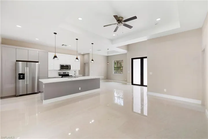 Kitchen with stainless steel appliances, an island with sink, open floor plan, white cabinetry, and hanging light fixtures