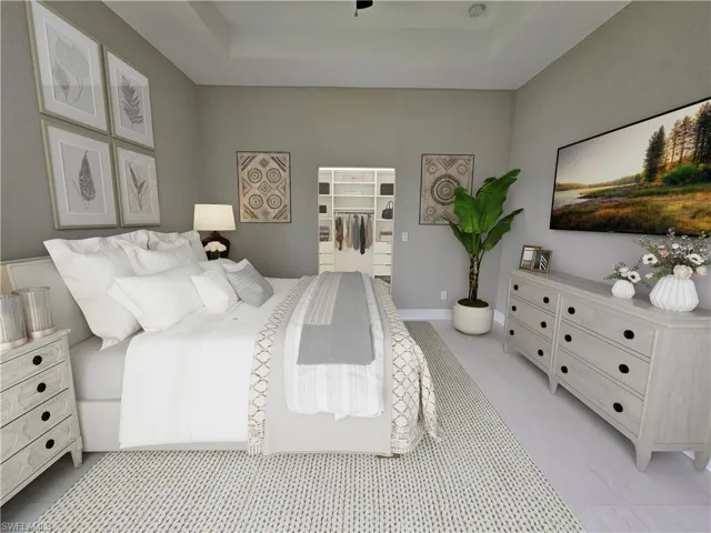 Tiled bedroom with a spacious closet, a tray ceiling, and ceiling fan