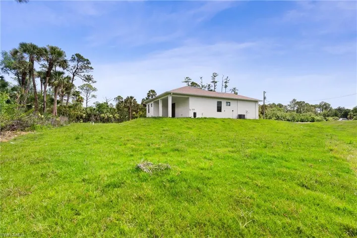 Rear view of house featuring a lawn and stucco siding