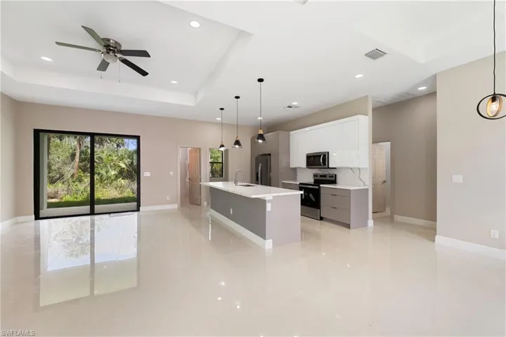 Kitchen featuring a center island with sink, pendant lighting, appliances with stainless steel finishes, white cabinetry, and recessed lighting