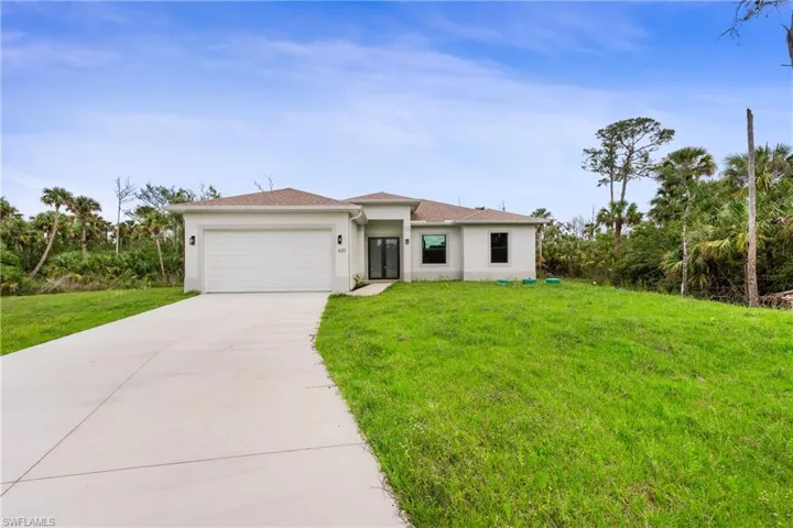 View of front facade featuring concrete driveway, a front lawn, a garage, and stucco siding