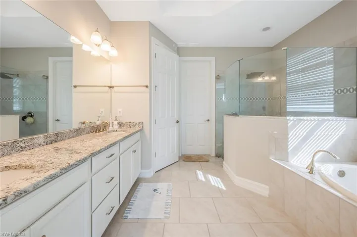 Full bathroom featuring double vanity, a stall shower, light tile patterned flooring, and a bath