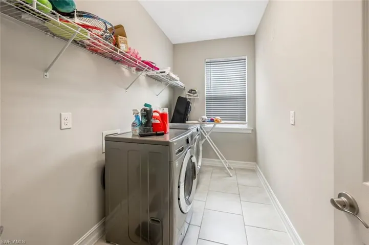 Laundry area with light tile patterned floors, washing machine and dryer, and an office area