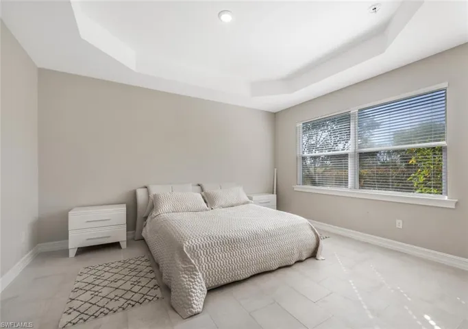 Bedroom featuring a tray ceiling and baseboards