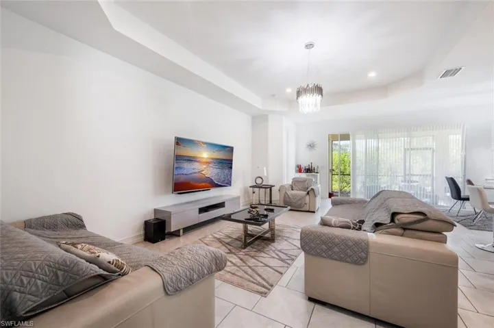 Living room featuring a raised ceiling, hanging lights, and light tile patterned floors