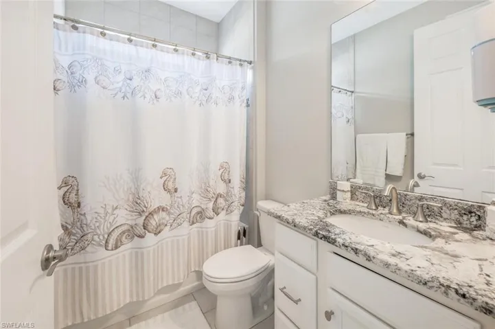 Full bathroom featuring vanity, shower / bath combo with shower curtain, and light tile patterned floors