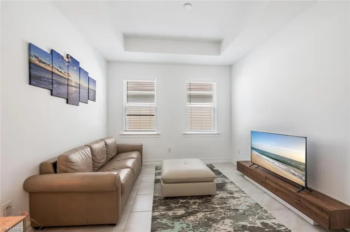 Living area with a raised ceiling and light tile patterned flooring