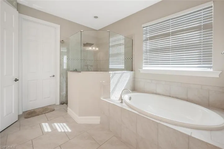 Bathroom featuring tiled shower, tile patterned flooring, and a bath