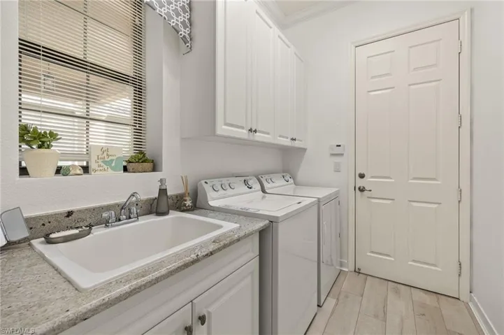 Cabinets, laundry sink, beautiful plank flooring and crown molding make this laundry room a winner!  Just beyond the Laundry room door is the 2 car garage with  extra insulation in the garage door and attic. Exterior surveillance cameras. Wiring for portable generator present.