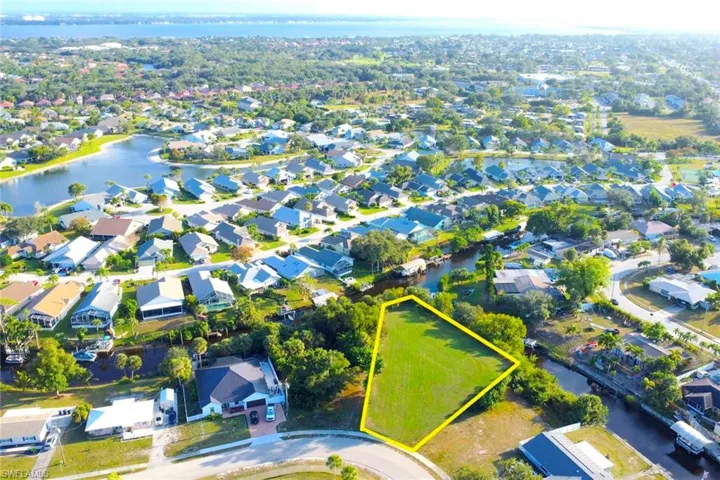 Aerial perspective of suburban area with property boundaries highlighted and a nearby body of water