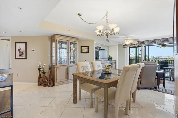 Dining room featuring a chandelier, a ceiling fan, and light tile patterned floors - Virtually Edited Image