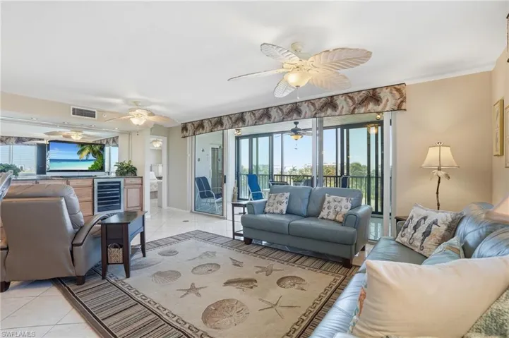 Living area featuring healthy amount of natural light, light tile patterned floors, wine cooler, and ornamental molding - Virtually Edited Image