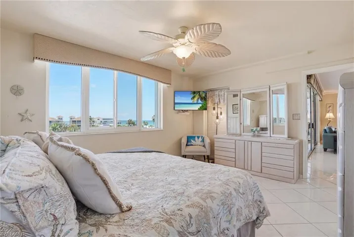 Bedroom with a ceiling fan and light tile patterned floors - Virtually Edited Image
