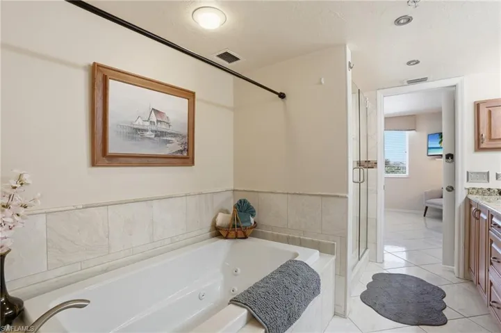 Full bath with vanity, a stall shower, a whirlpool tub, and light tile patterned flooring - Virtually Edited Image