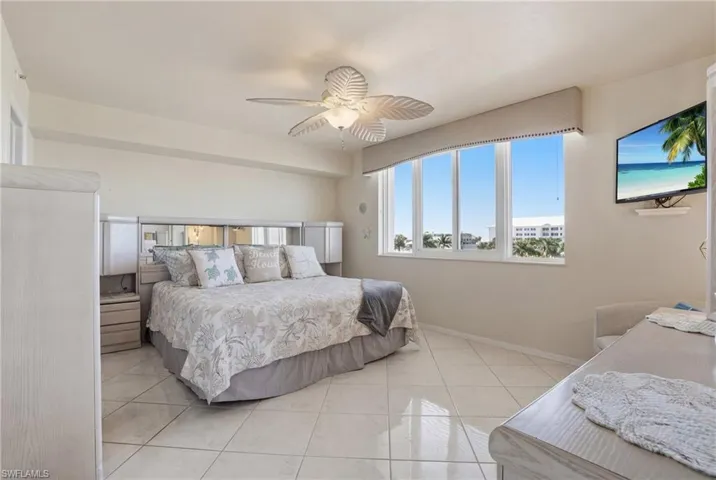 Bedroom with light tile patterned floors and ceiling fan - Virtually Edited Image