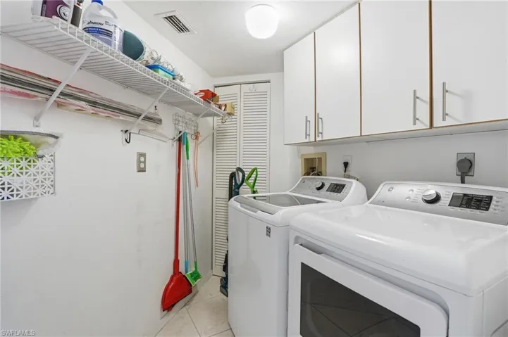 Laundry area with cabinet space, independent washer and dryer, and light tile patterned floors - Virtually Edited Image