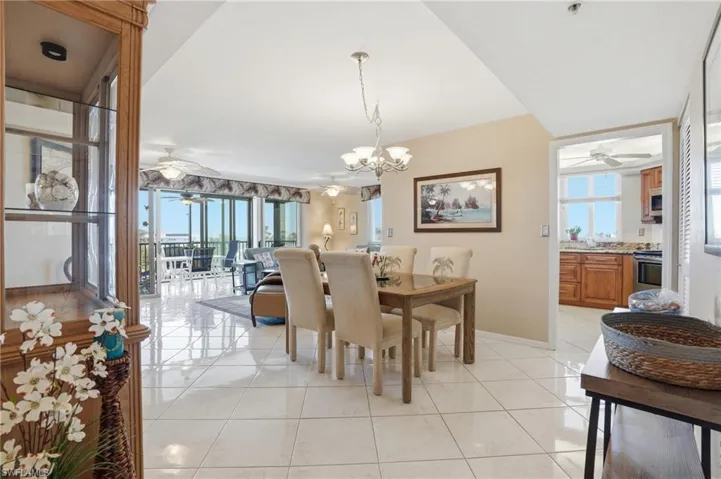 Dining area featuring ceiling fan, hanging lights, light tile patterned flooring, and healthy amount of natural light - Virtually Edited Image