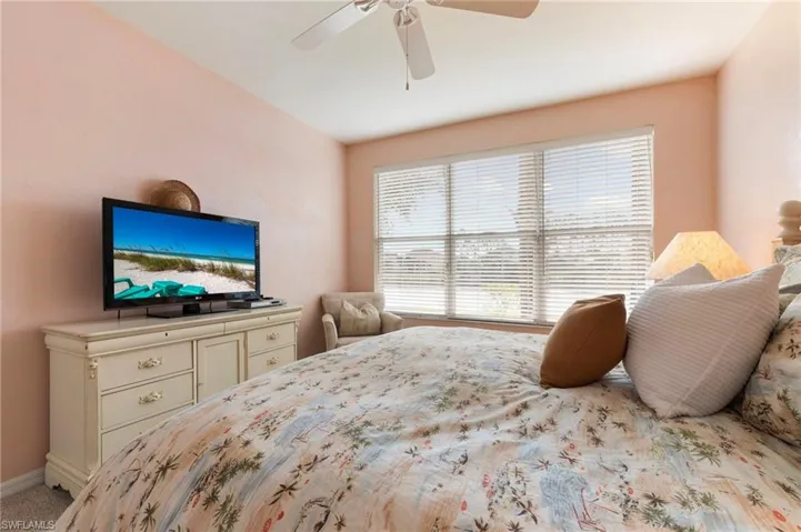 Carpeted bedroom with a ceiling fan and baseboards