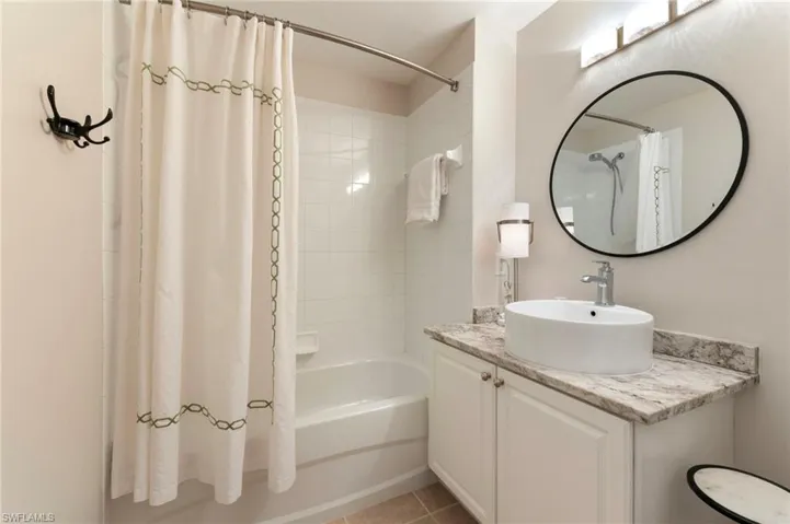Bathroom with shower / bathtub combination with curtain, vanity, and light tile patterned floors