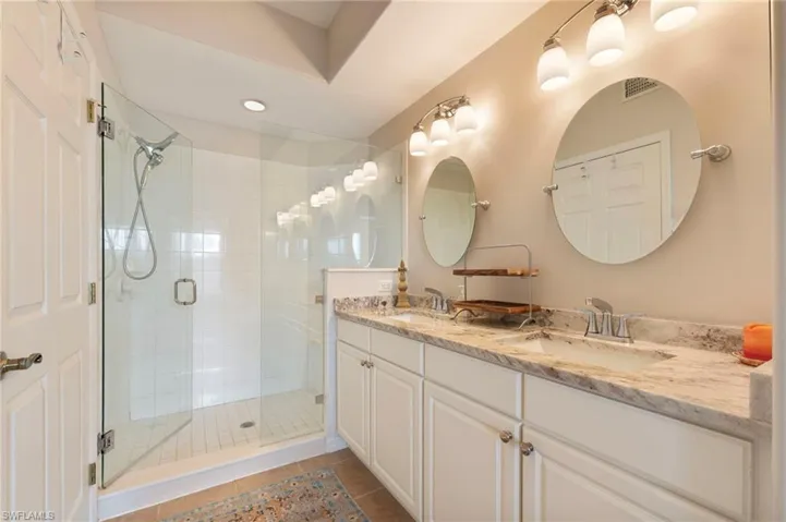 Full bath featuring double vanity, a shower stall, dark tile patterned floors, and recessed lighting
