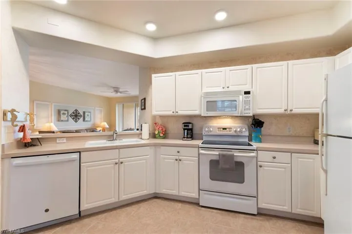 Kitchen featuring white appliances, white cabinetry, light countertops, and recessed lighting
