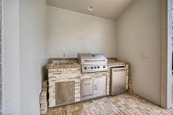 View of patio featuring area for grilling, glass enclosure, and ceiling fan