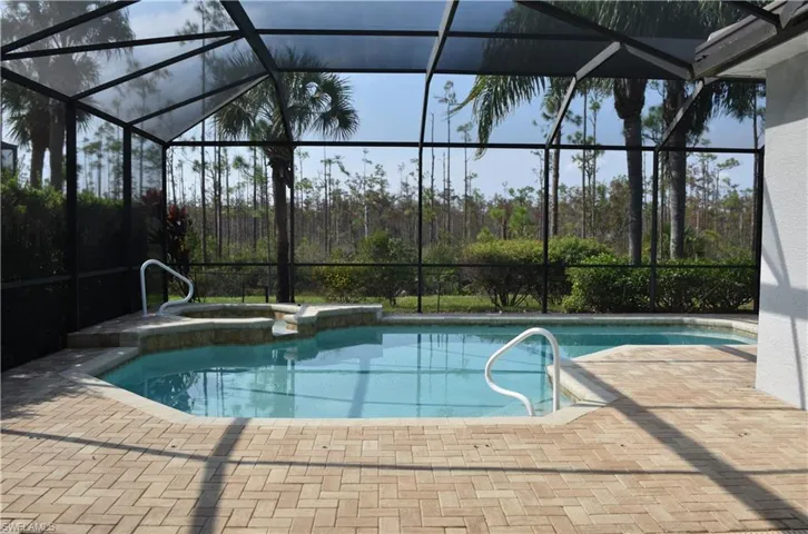 View of pool featuring an in ground hot tub, a patio, and glass enclosure