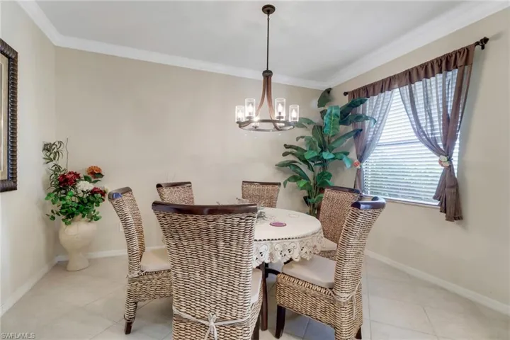 Dining room featuring a notable chandelier, light tile patterned floors, and ornamental molding