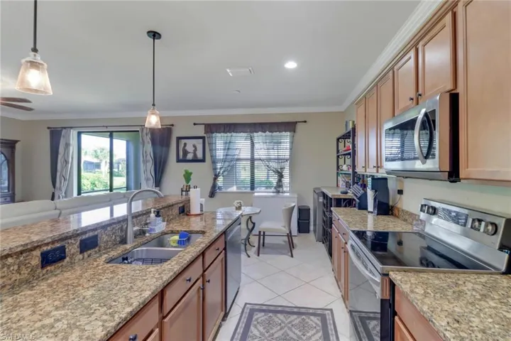 Kitchen featuring light tile patterned flooring, pendant lighting, stainless steel appliances, ornamental molding, and sink